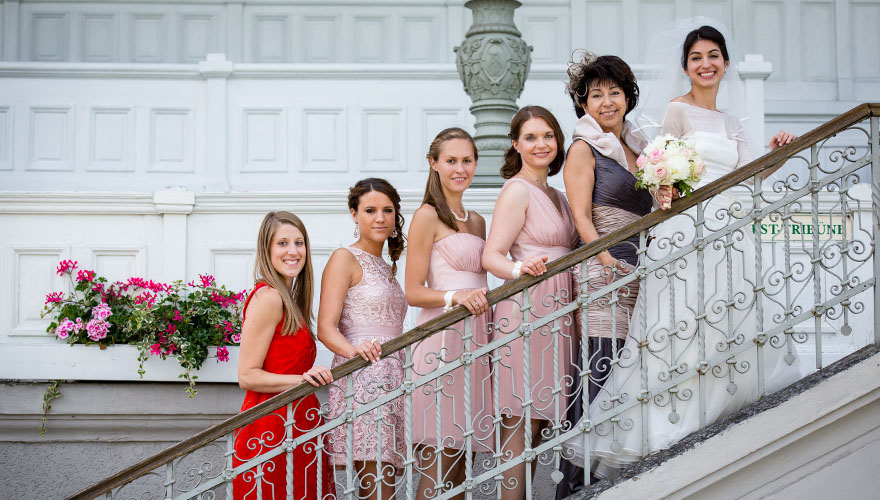 Eine Braut und fünf Brautjungfern stehen auf einer Treppe welche auf eine Tribüne mit alter Holzvertäfelung führt.