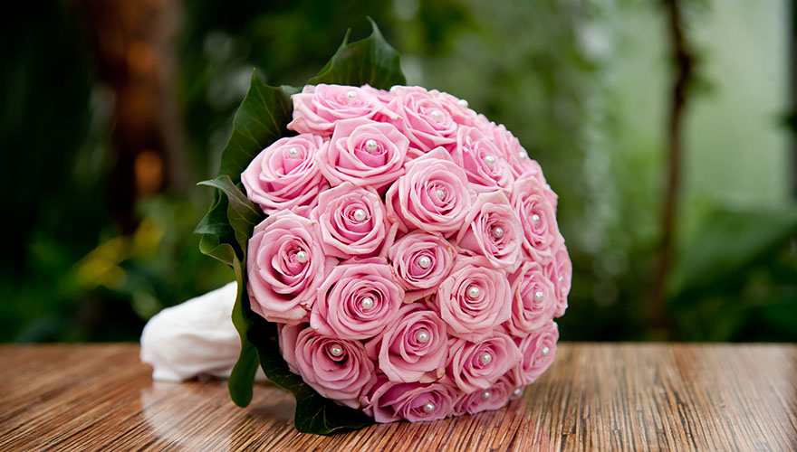 Ein Brautstrauss mit Rosen. In den Blüten stecken Perlen.