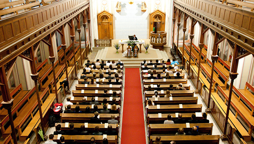 Eine Hochzeit. Der Fotograf steht bei der Orgel oben und sieht auf die Hochzeitszeremonie hinab.