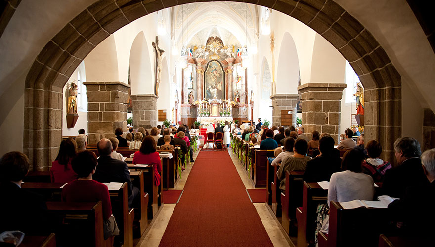 Der Fotograf steht am hinteren Ende der Kirche. Vorne findet eine Trauung statt. Die andächtigen Gäste lauschen der Eheschliessung.