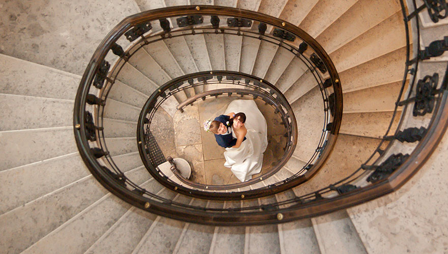Ein Brautpaar steht am Ende einer Wendeltreppe. Der Fotograf ist schon im dritten Stockwerk und bemerkt das Brautpaar welches ihn beobachtet.
