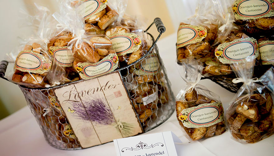 Auf einem Tisch bei einer Hochzeit stehen Orange-Lavendel-Cantuccini in Körben. Es handel sich dabei um eine Backspezialität aus Italien.