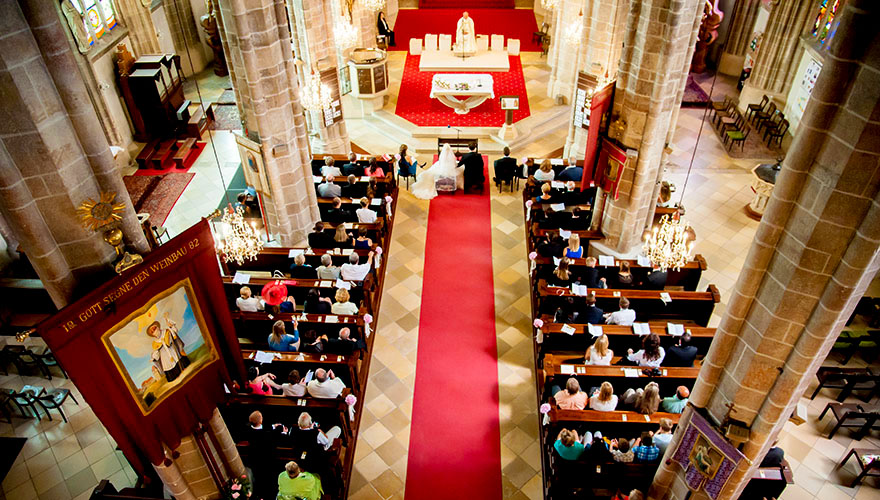 Eine Hochzeit in einer sehr grossen Kirche. Der Fotograf steht bei der Orgel ganz oben und erfasst das ganze Geschehen von oben.